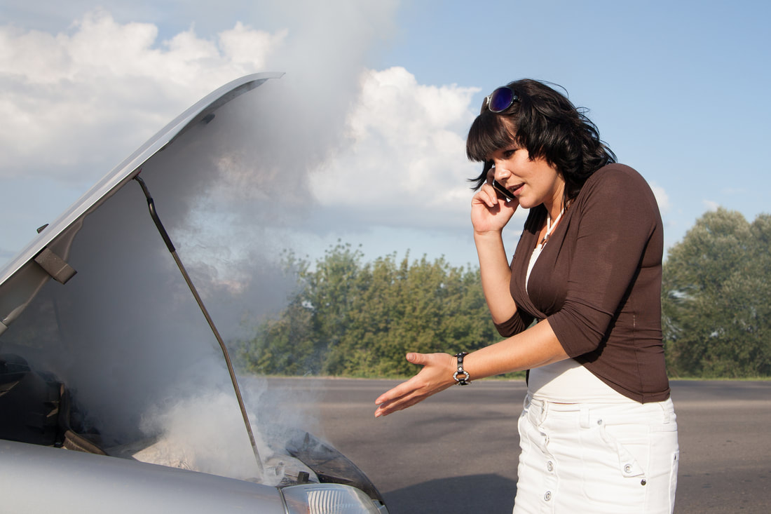 woman in brockton ma on the phone with tow truck company because car engine is smoking