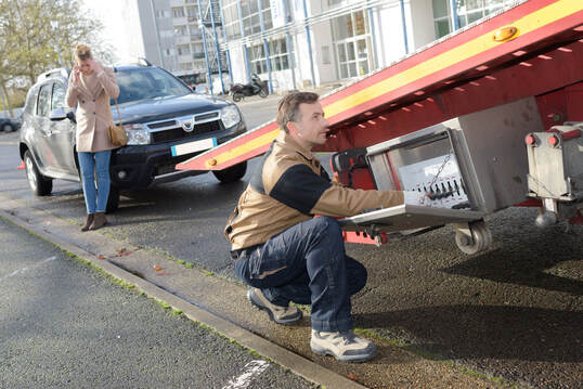 Tow truck driver in Brockton, MA loading woman's car onto flatbed tow truck